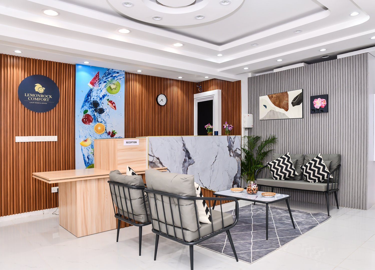 Modern hotel reception area with a marble desk, seating area, wall art, and decorative lighting.
