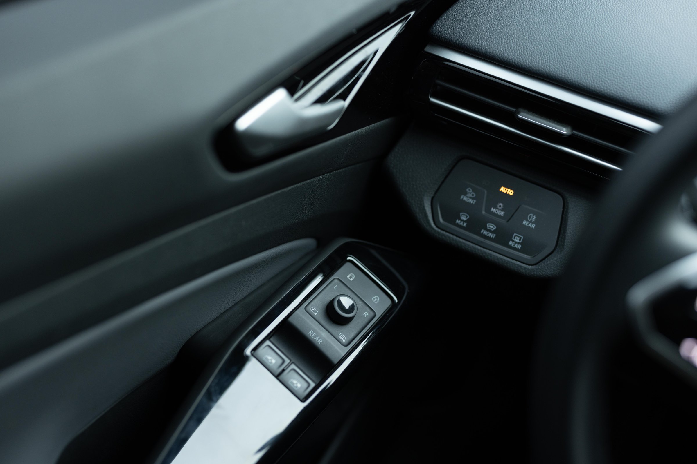 Window control buttons in modern luxury electric car. Car leather interior details of door handle with windows controls and adjustments. Car window controls. Door handle with power window control.