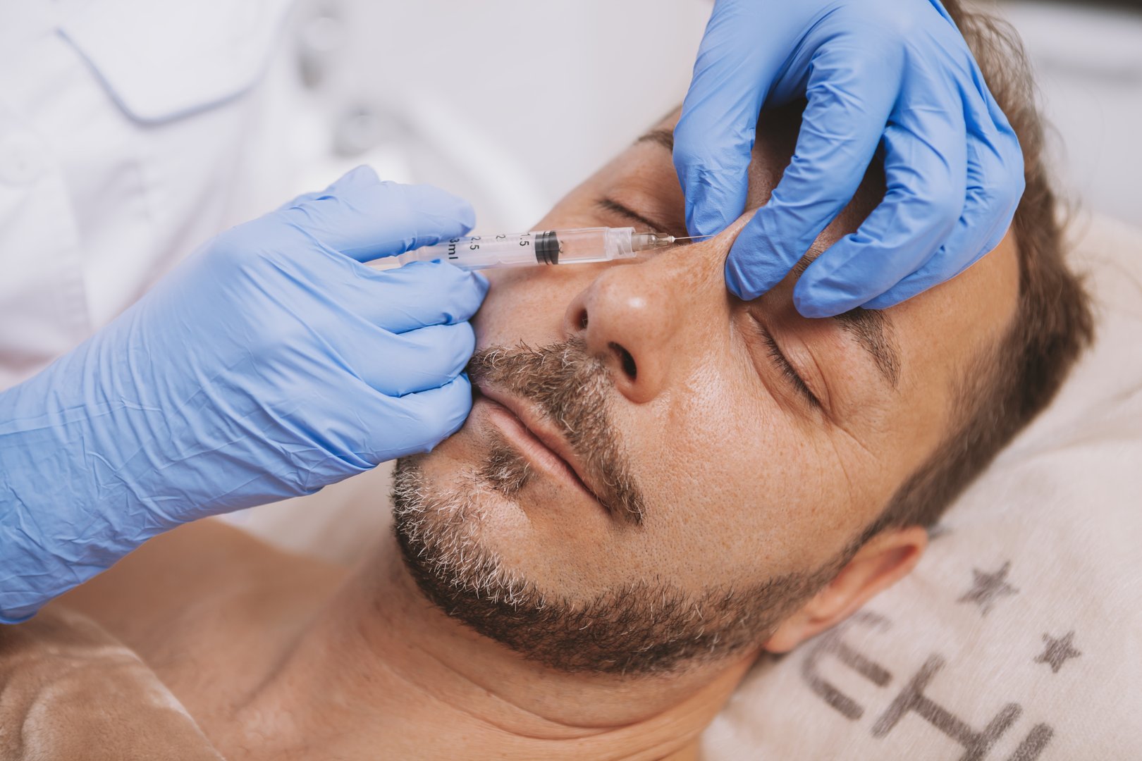 Mature man getting non-surgical nose job at beauty salon. Male client receiving filler injections in his nose, getting rhinoplasty
