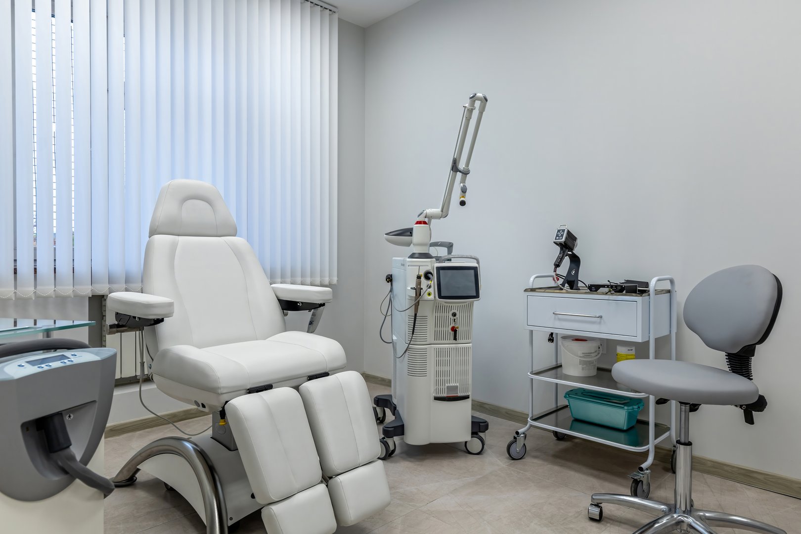 A modern clinic room features specialized laser equipment and an adjustable chair, ensuring a comfortable setting for medical procedures