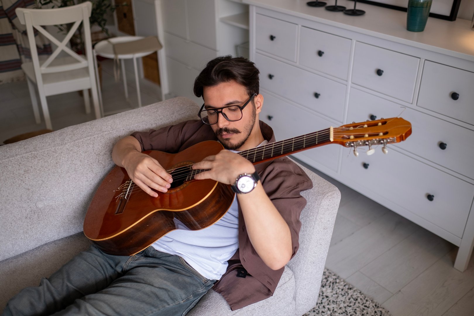 Male teenager singing song playing acoustic guitar reading text on smartphone application screen enjoy art hobby. Man adolescent singer vocalist repetition string musical instrument chord melody