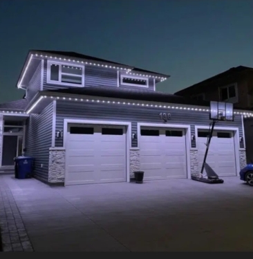 Multi-colour permanent LED lighting display across a home's complex roofline and peaks