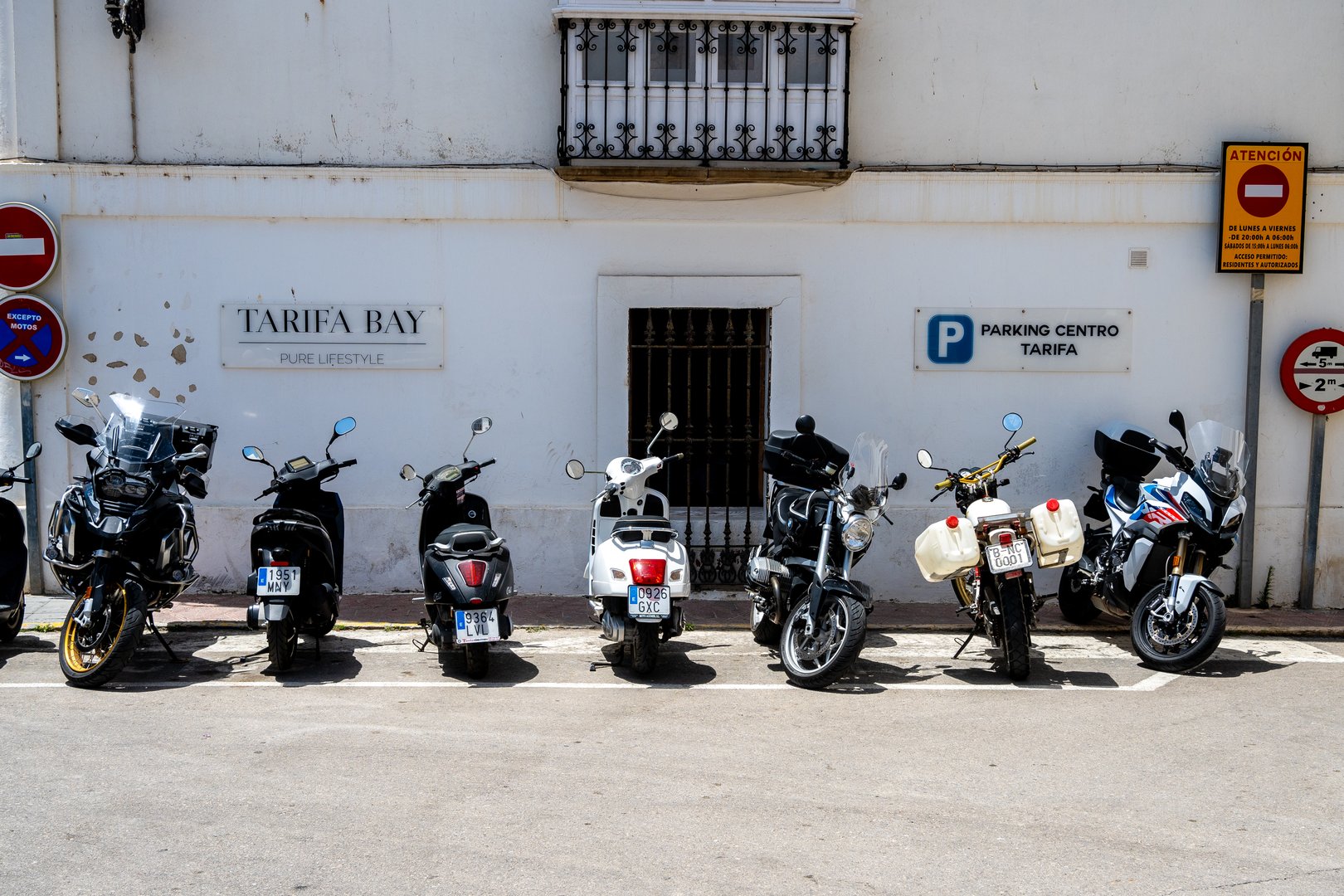 TarifaÂ  Caediz - Spain - 05-30-2024: Row of parked motorcycles in front of white building labeled Tarifa Bay.
