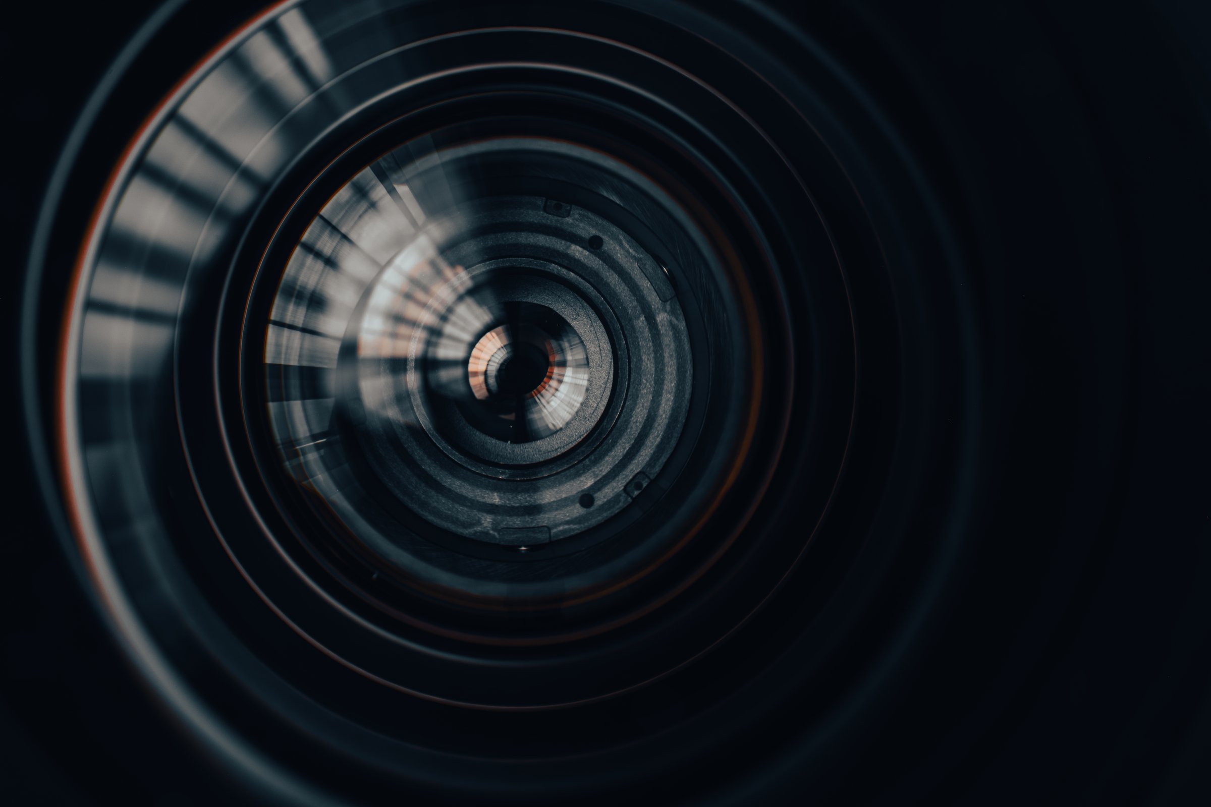 A mesmerizing macro shot peering into the complex internal elements and glass coatings of a high-end camera lens, showcasing radial symmetry, reflections, and precision optical engineering