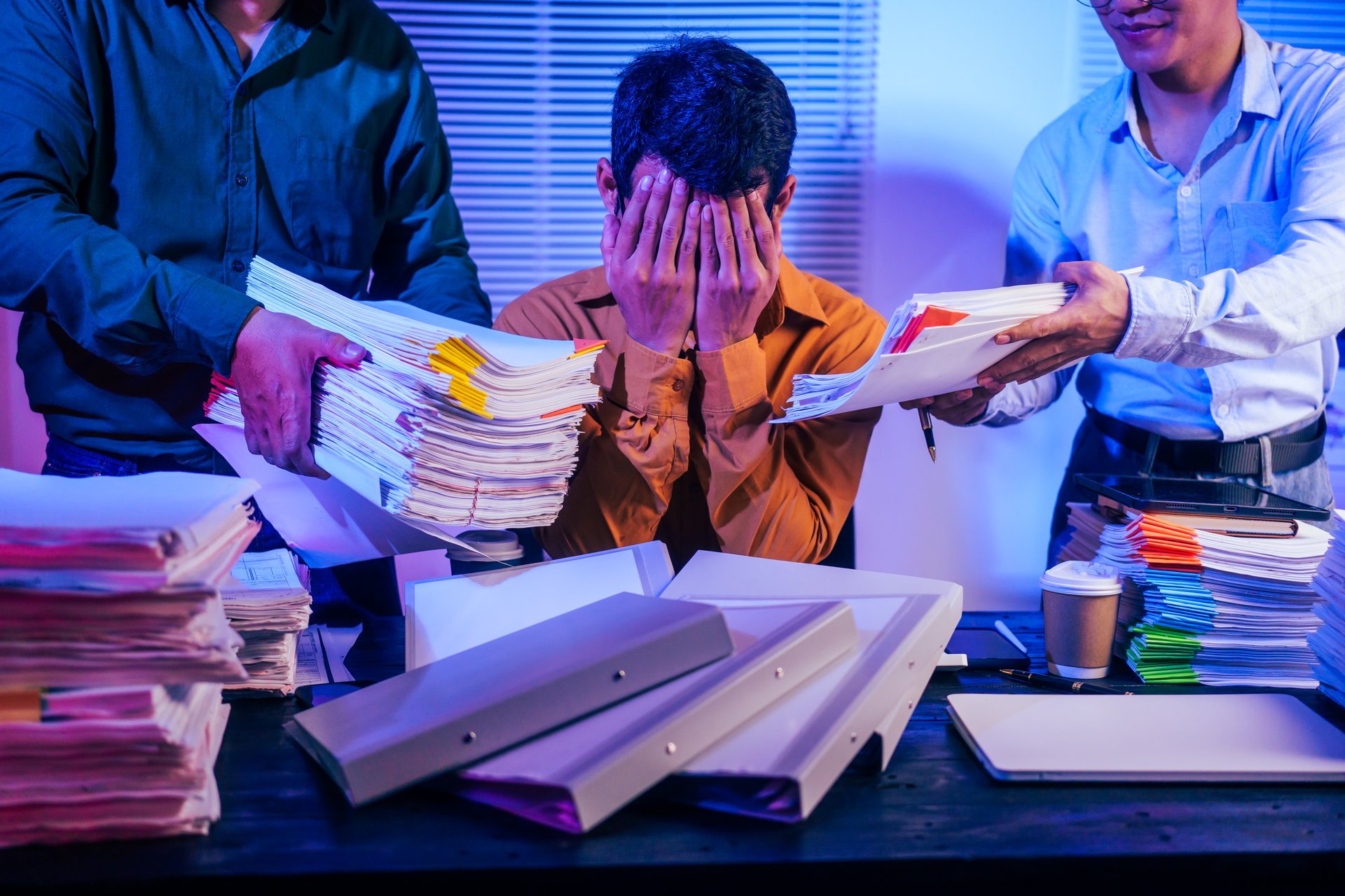 Three men work overtime at night, stressed and overloaded with tasks. They are exhausted, checking documents, and discussing plans. Despite their efforts, they struggle to complete the work on time