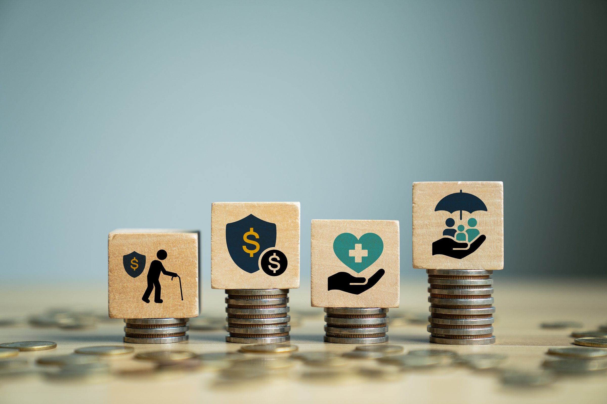 Financial and insurance planning concept with wooden blocks on stacked coins showing retirement, money protection, health care, family coverage, symbolizing wealth security, savings, risk management