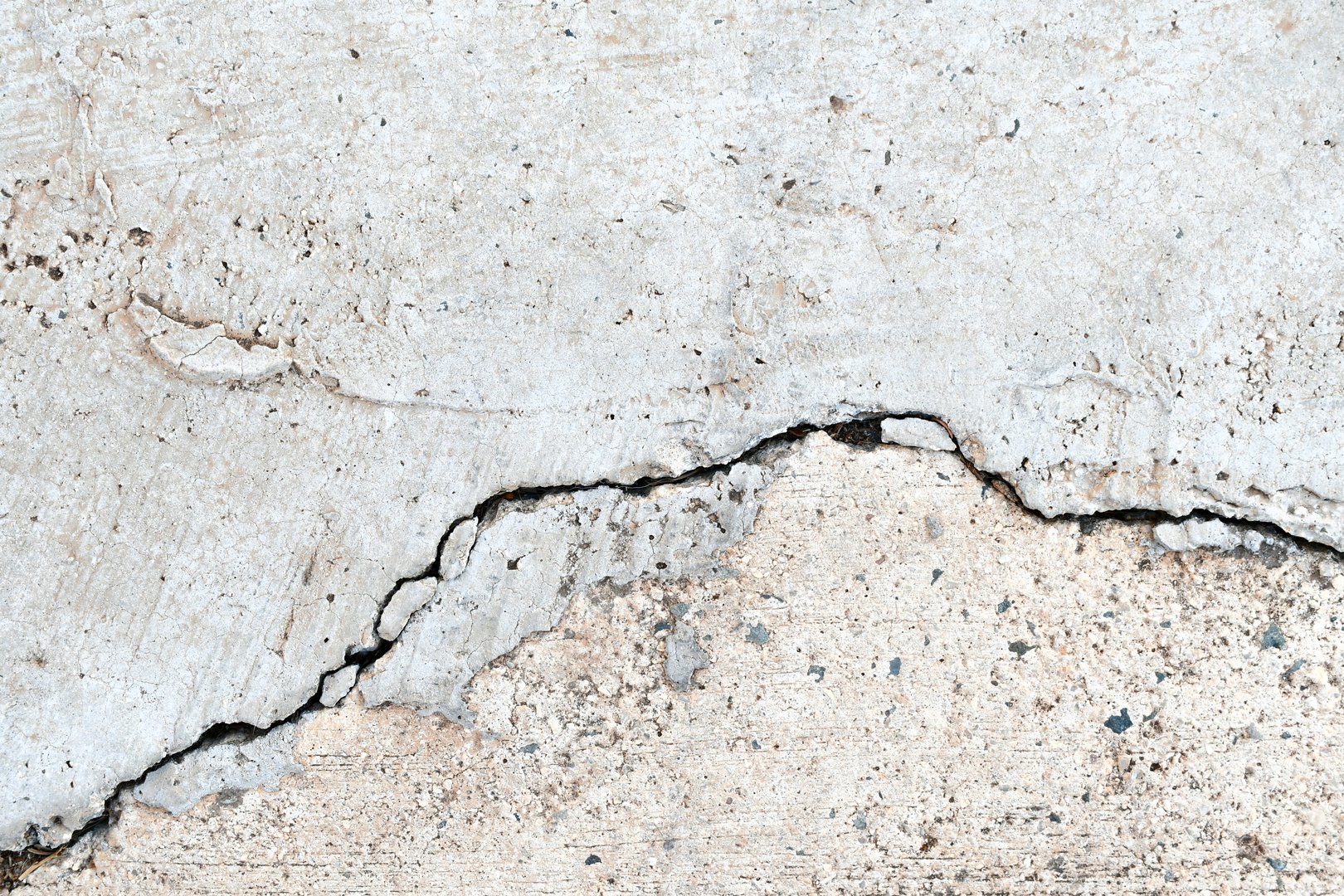 Uneven and damaged basement concrete floor. Grunge and rough cracked cement surface.
