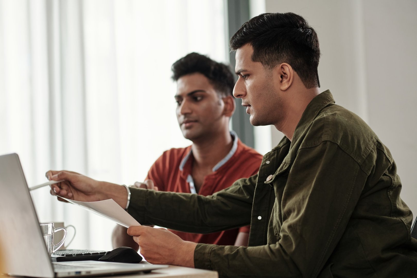 Software developer pointing at computer screen when sharing his idea with colleague