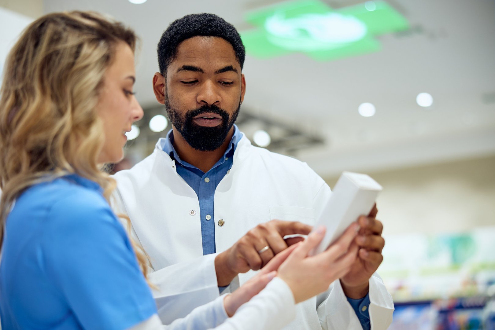 A pharmacist provides guidance to a customer about a product in a pharmacy.