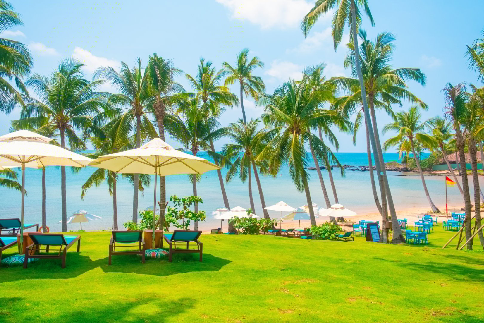 Tropical beach resort with lounge chairs and umbrellas overlooking turquoise sea, relaxing summer vacation scene with palm trees and ocean breeze on sunny day, Phu Quoc island, Vietnam. Summer vacation destination in Asia.