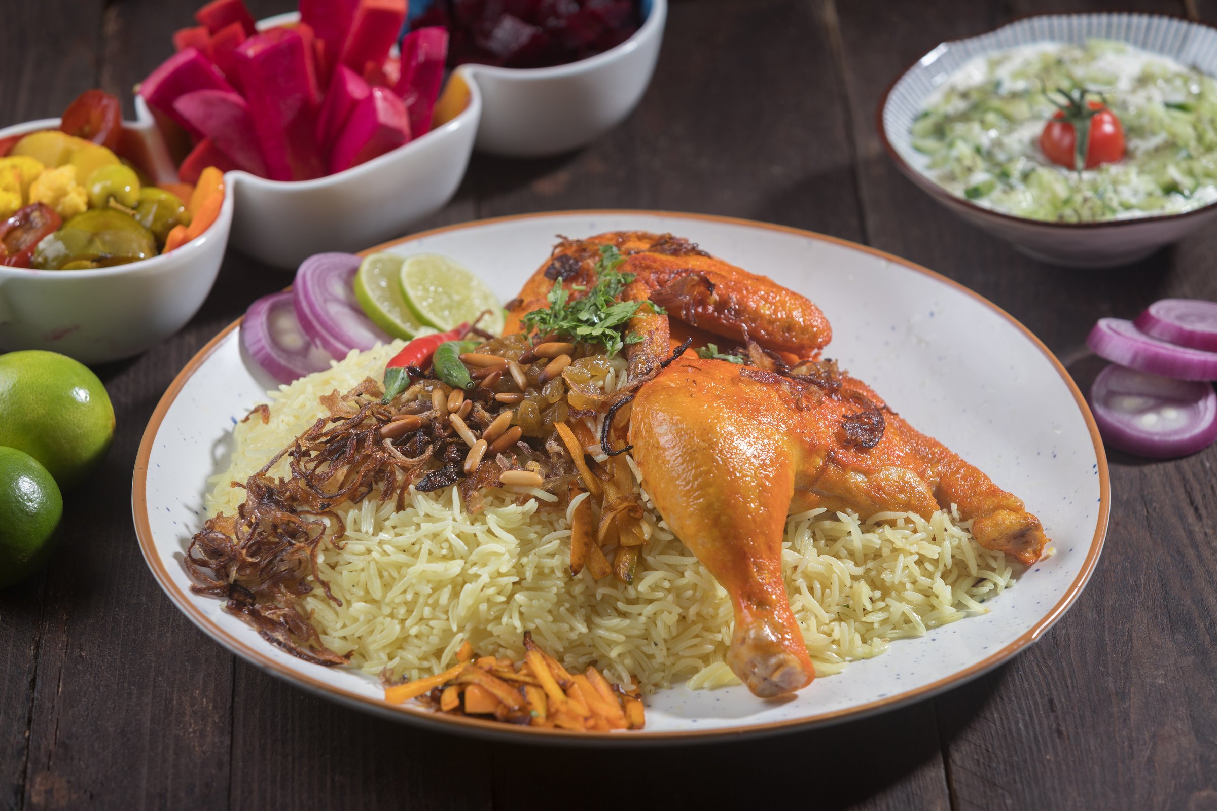 Chicken Machboos served on a white plate features roasted chicken, spiced rice, and various side dishes side view of gourmet Arabian meal