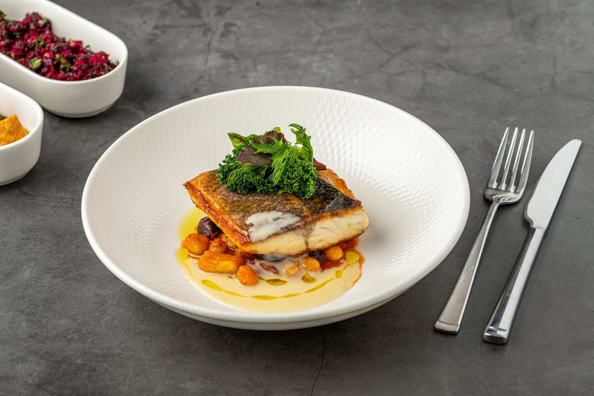 Crispy-skinned pan-seared fish fillet with chickpeas, creamy sauce, and fresh greens