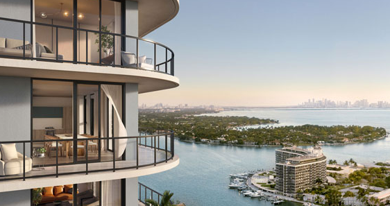 Modern high-rise with glass balconies overlooking a scenic waterfront and city skyline in the distance.