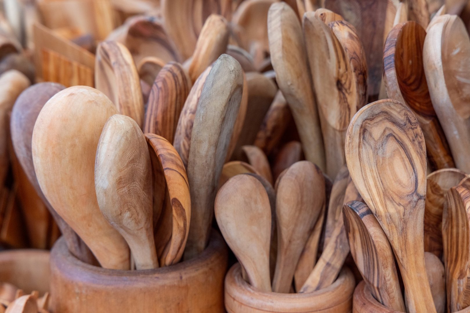 Background of handcrafted wooden spoons in various shapes and sizes with smooth polished surfaces and natural grain patterns