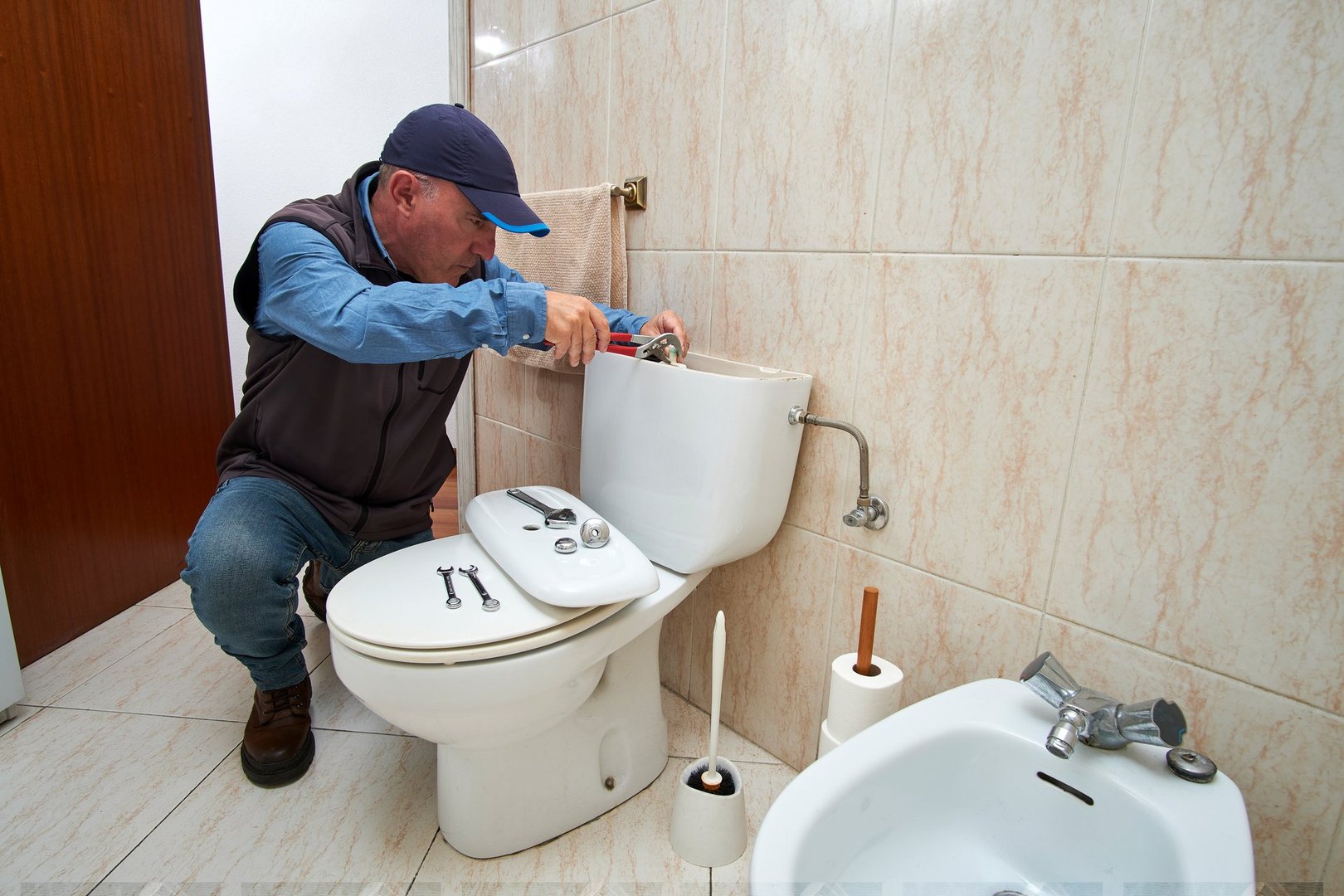 Professional plumber repairing a toilet cistern