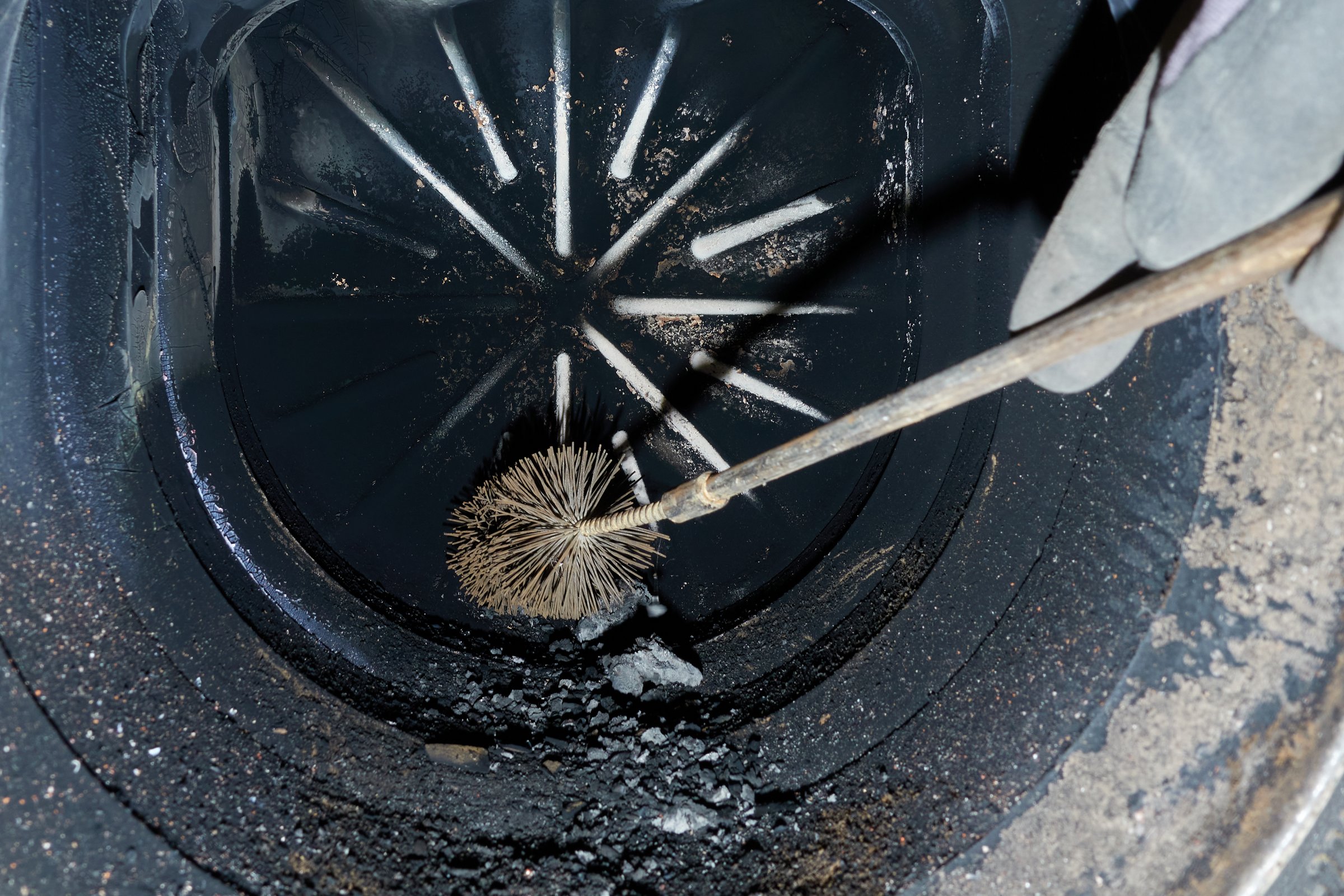 Cleaning brush in an old cast iron heater, removes black soot and combustion residues. To ensure economical operation and energy-conscious heating.