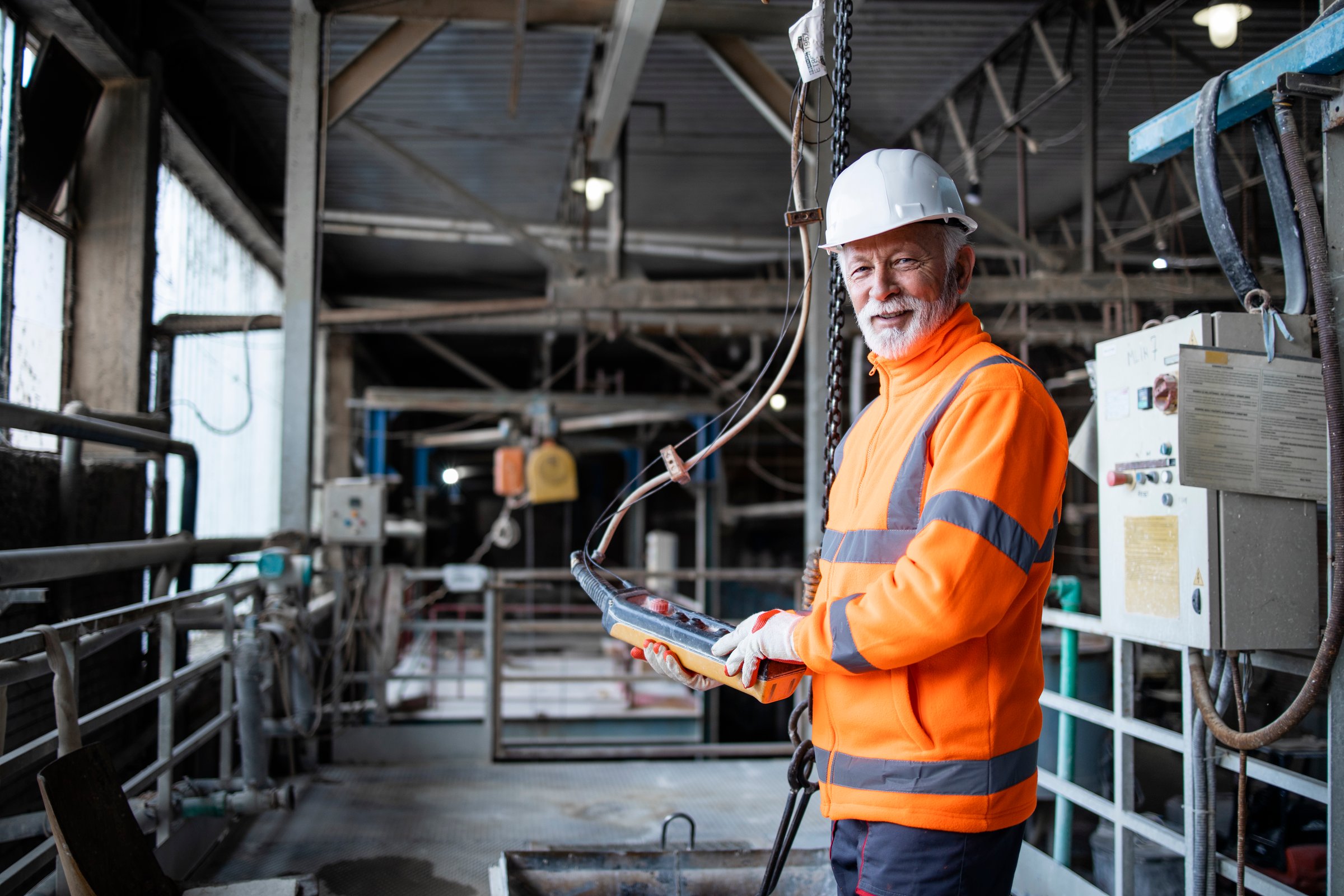Close up view of factory worker operating industrial machine with push button joystick in production hall. Employee working on industry production machine.