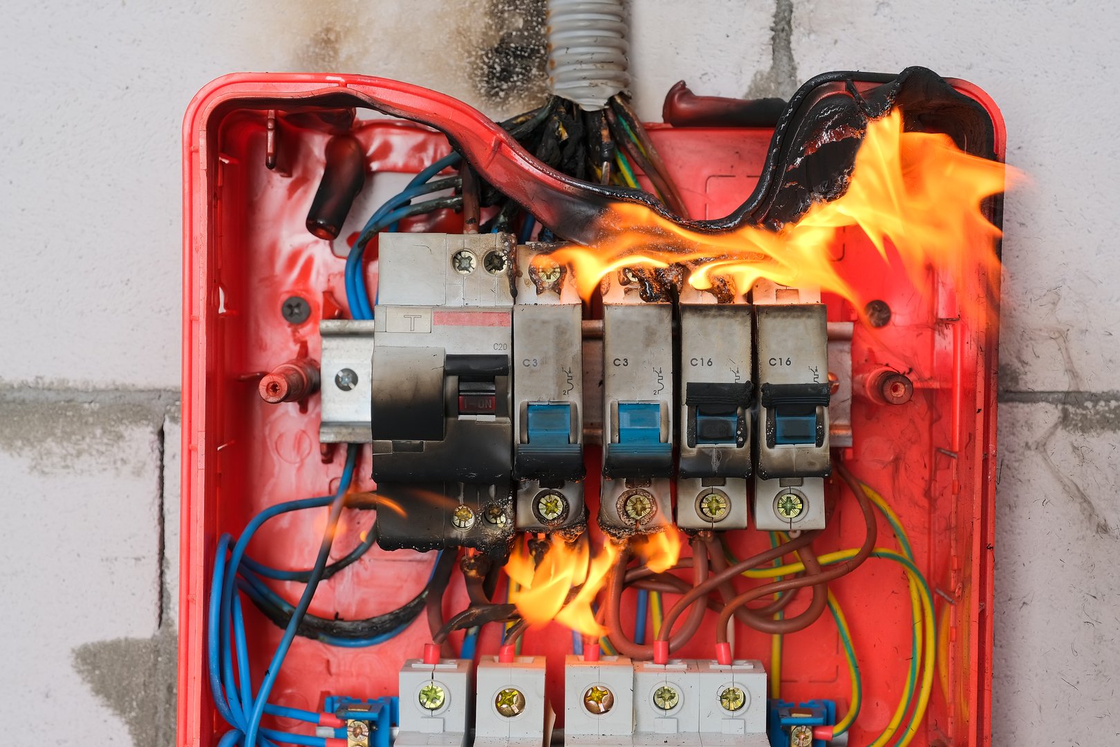 Burning switchboard from overload or short circuit on wall close-up. Circuit breakers on fire from overheating due to poor connection or poor quality wires. Faulty home wiring concept