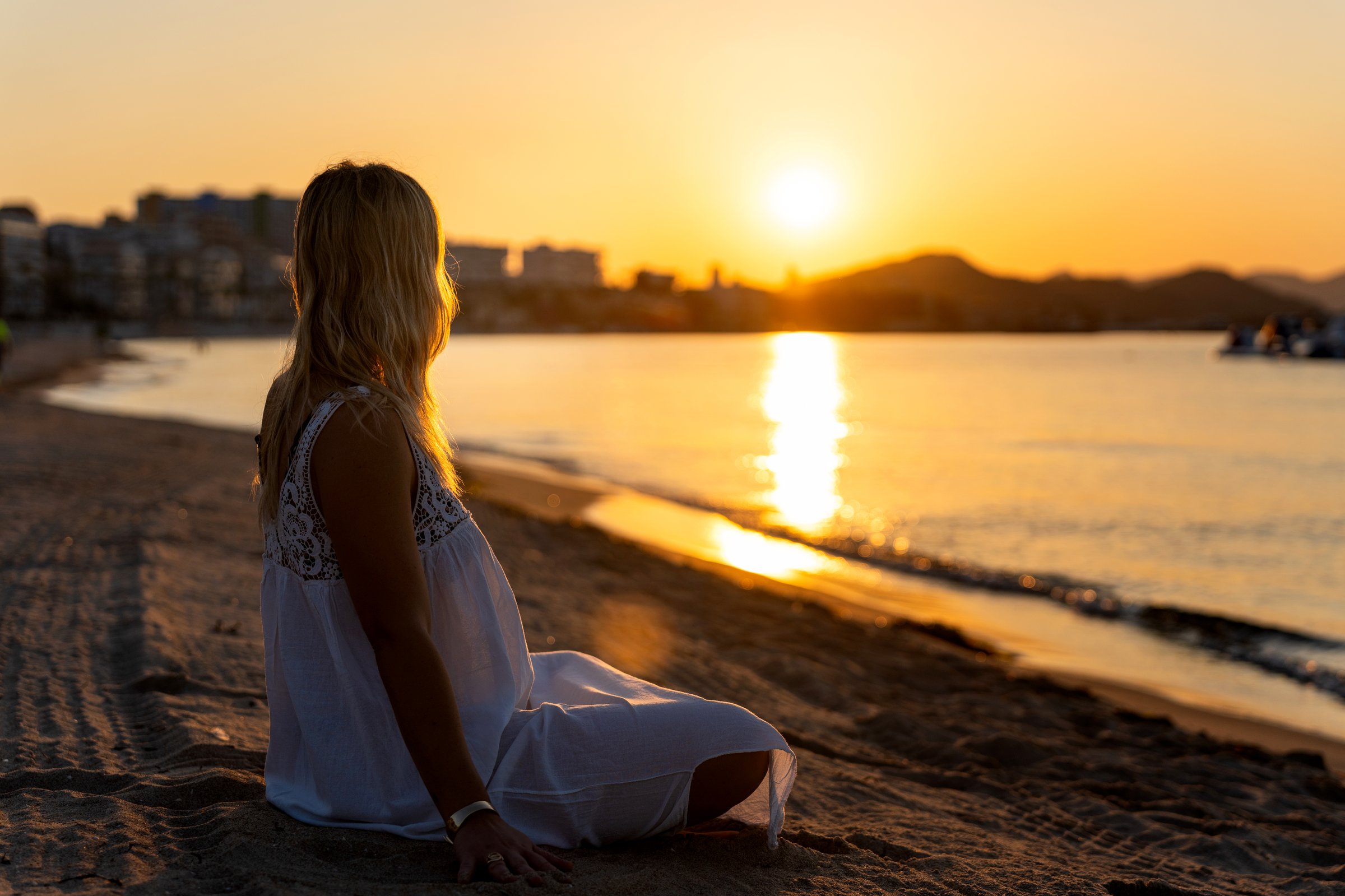 Argentine woman practicing yoga and meditating on the beach at sunrise in villajoyosa, spain, enjoying the peaceful atmosphere