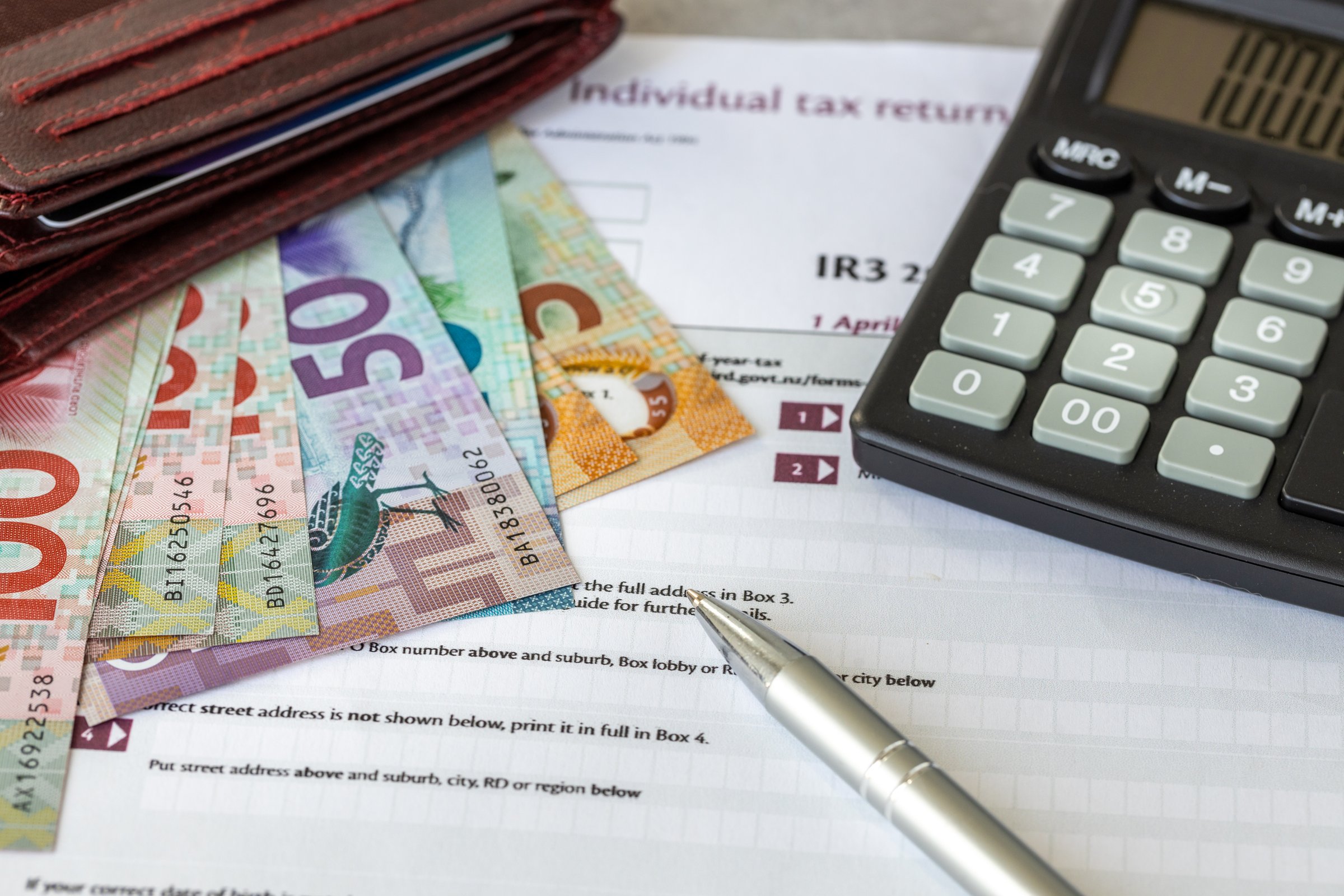 New Zealand Individual tax return. tax forms and New Zealand dollars, calculator and pen, financial concept