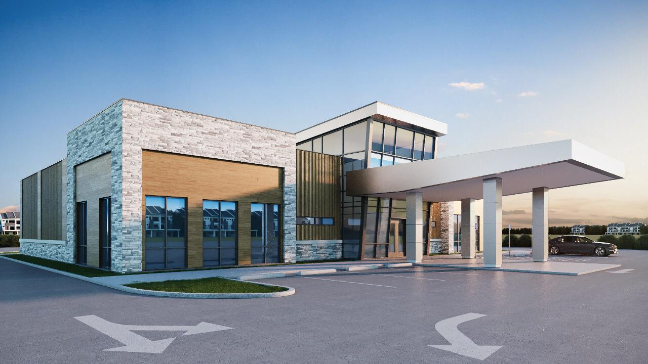 Modern building exterior with large windows, stone and wood paneling, and a covered entryway in a spacious parking lot.