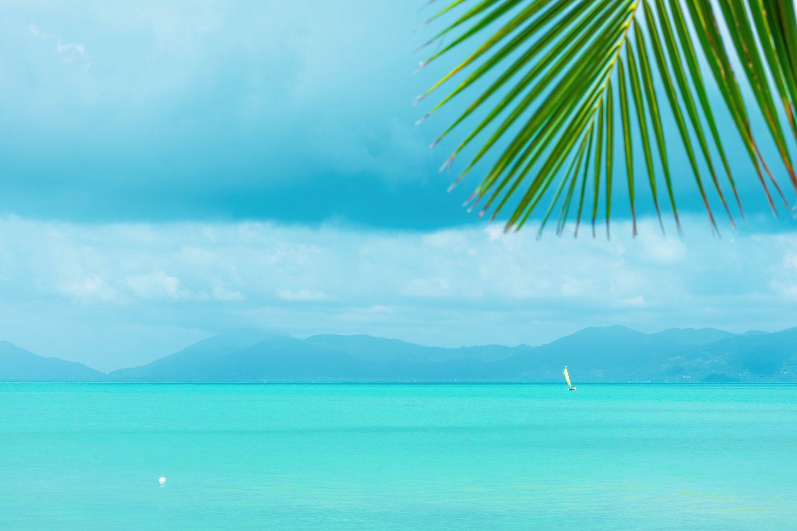 Turquoise sea view with sailboat in the distance