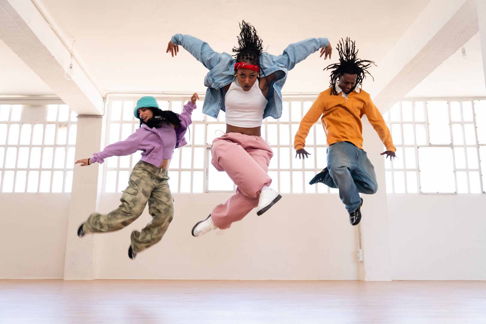 Young group of multiethnic hip-hop dancers wearing colorful urban streetwear dancing - Stylish multiracial rap crew portrait in the dance studio