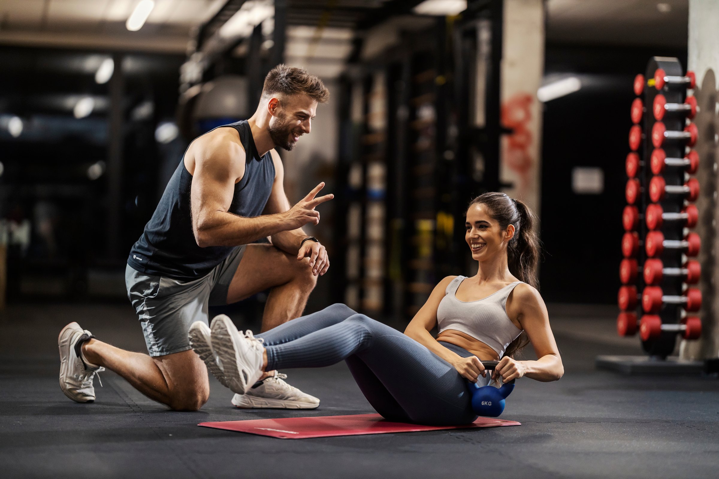 A sportswoman is dong russian twist with her personal trainer in a gym