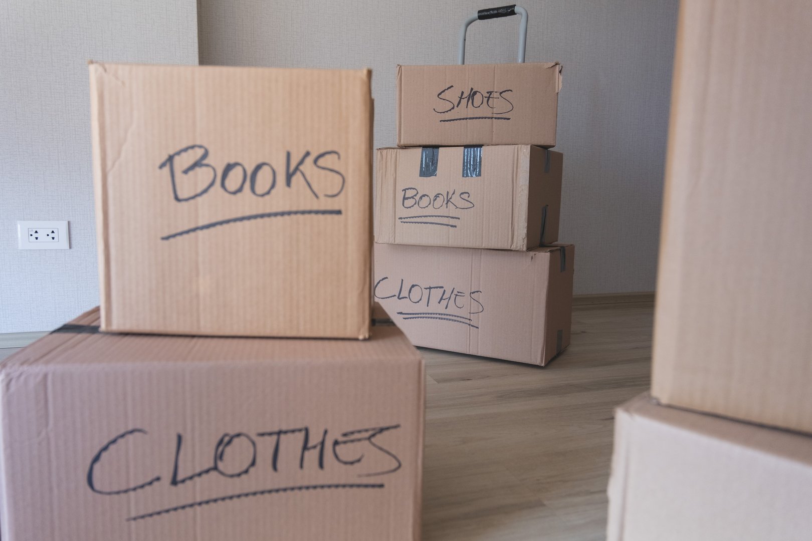 A stack of boxes with the words books and clothes written on them. The boxes are piled on top of each other, and the labels suggest that they are being packed for a move