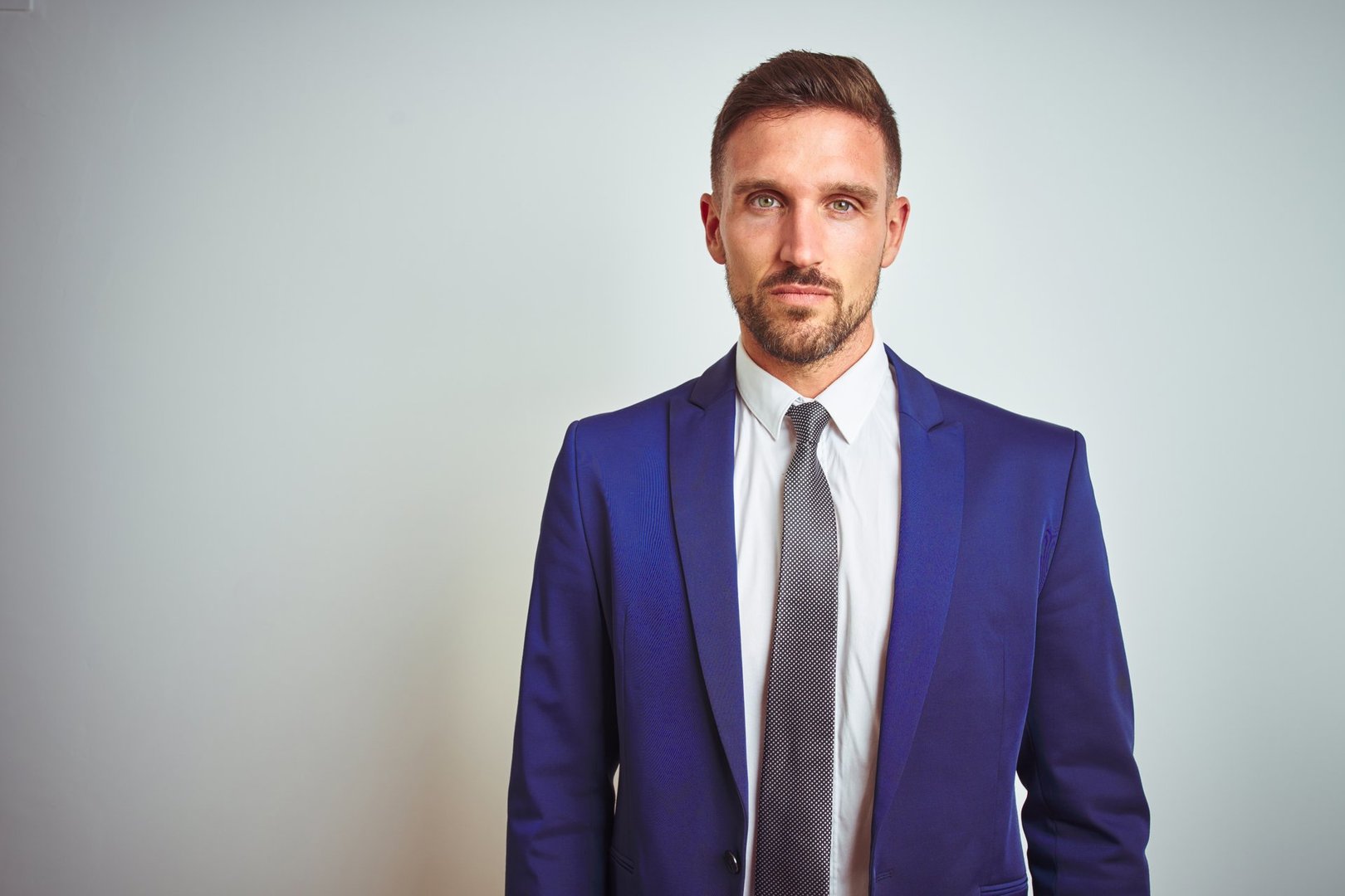 Young handsome business man over white isolated background with serious expression on face. Simple and natural looking at the camera.