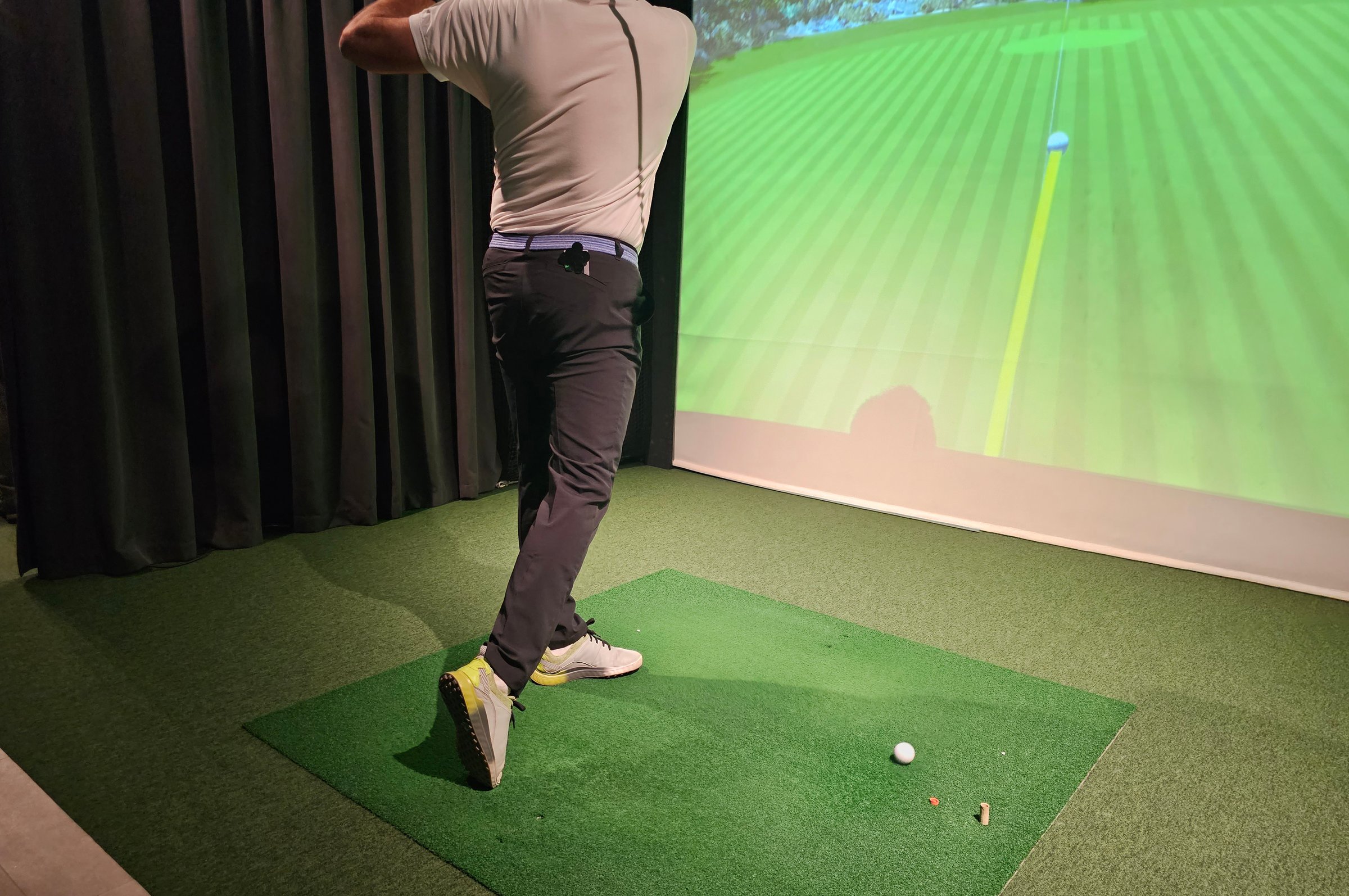 Golfer swings in indoor simulation