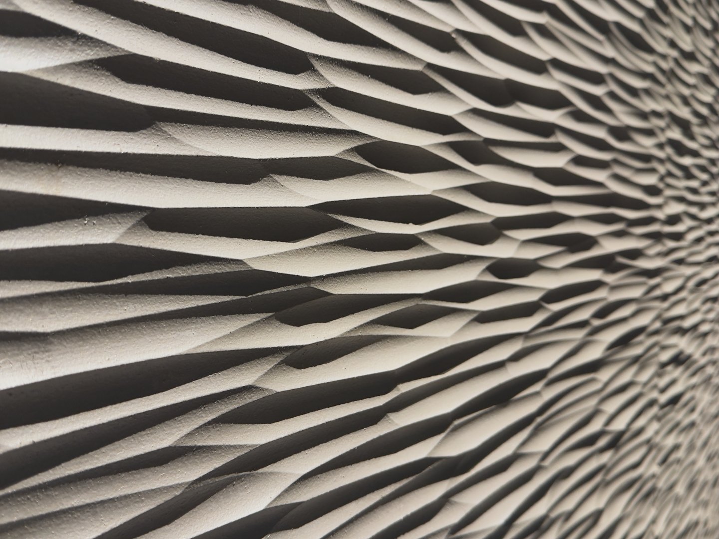 Textured wall pattern with angled light casting shadows in waves.