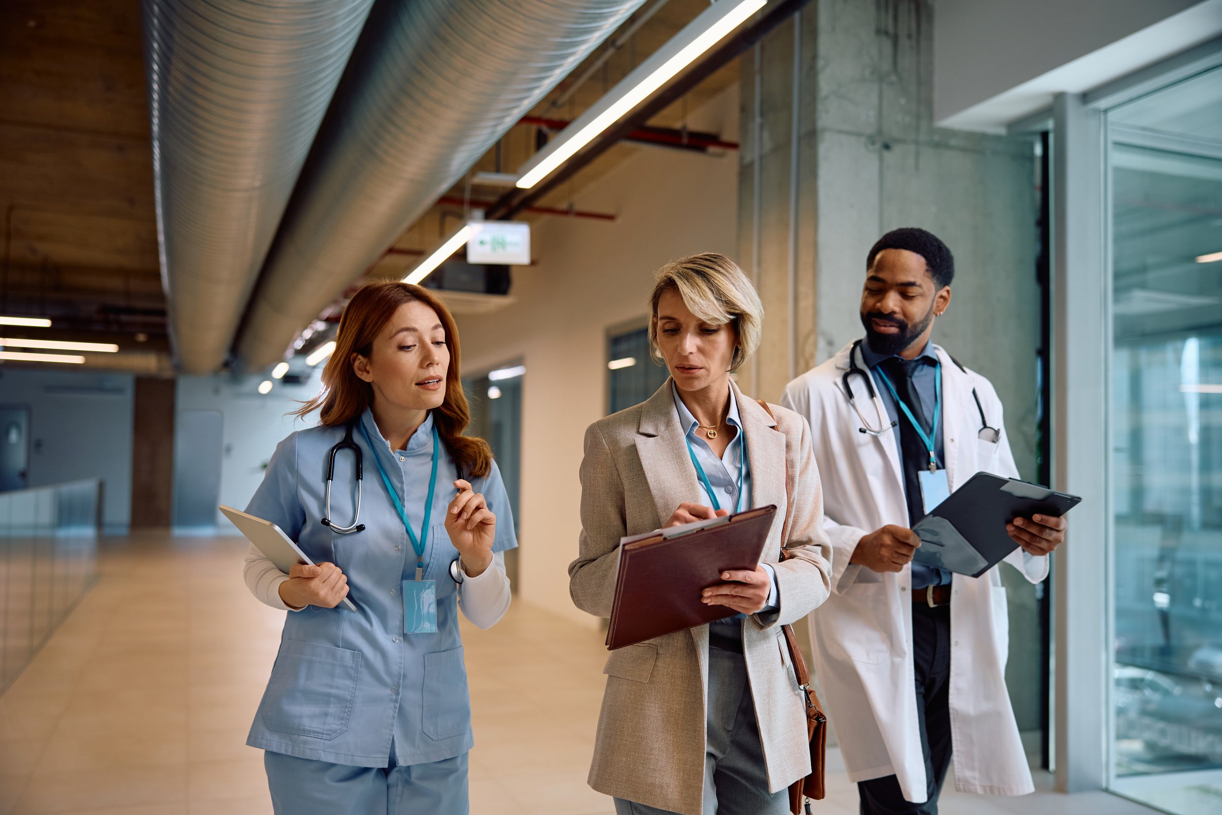 Hospital administrator analyzing medical data with a nurse and African American doctor.