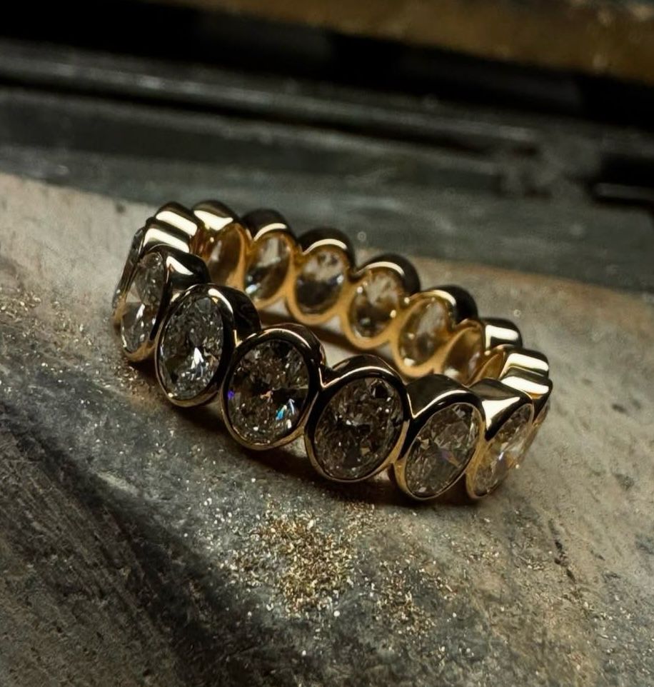 Gold ring with teardrop-shaped diamonds on a textured surface.