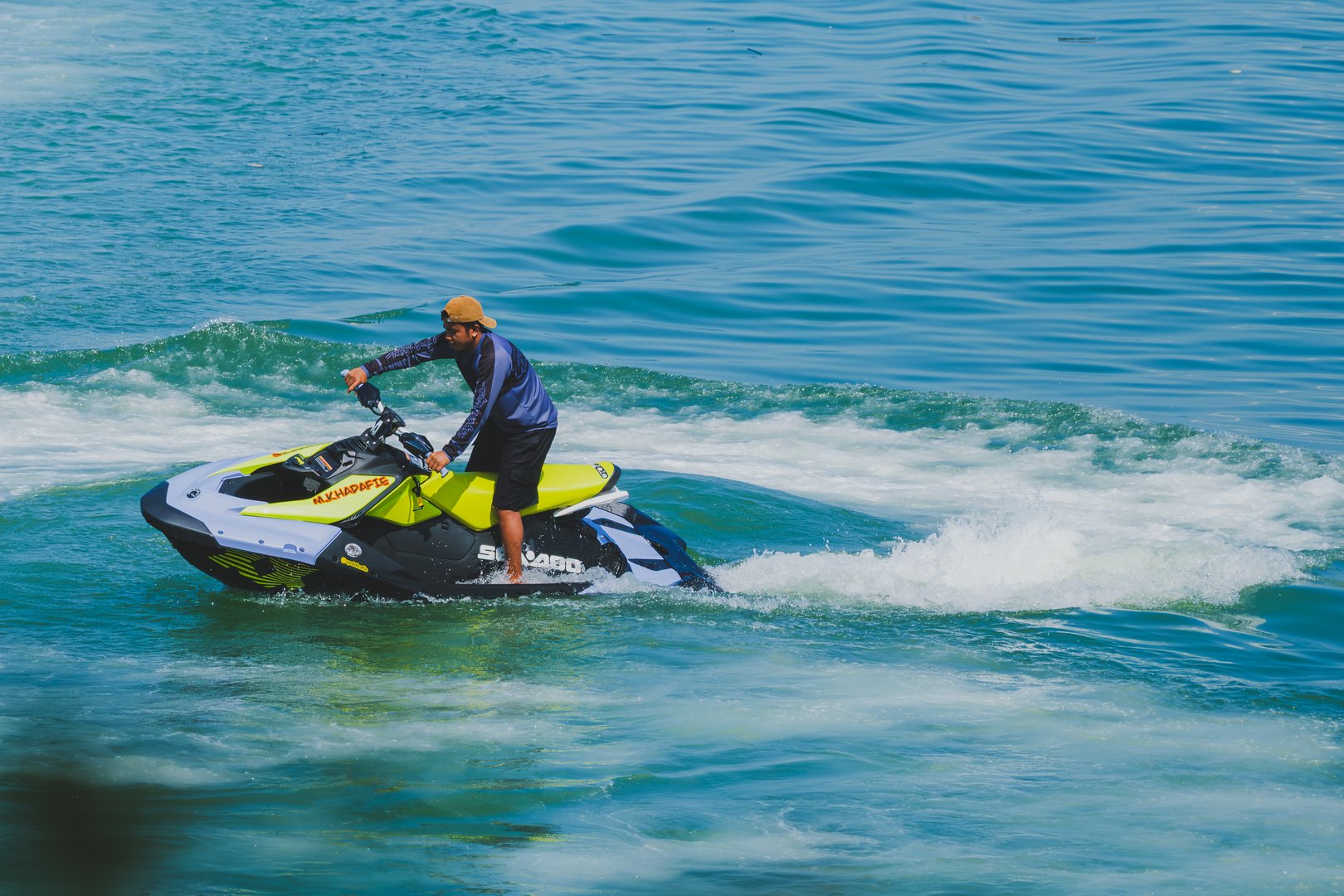 Balikpapan, Indonesia - May 04th 2025. A man skillfully riding a yellow Sea-Doo jet ski across vibrant turquoise waters, creating waves as he maneuvers.