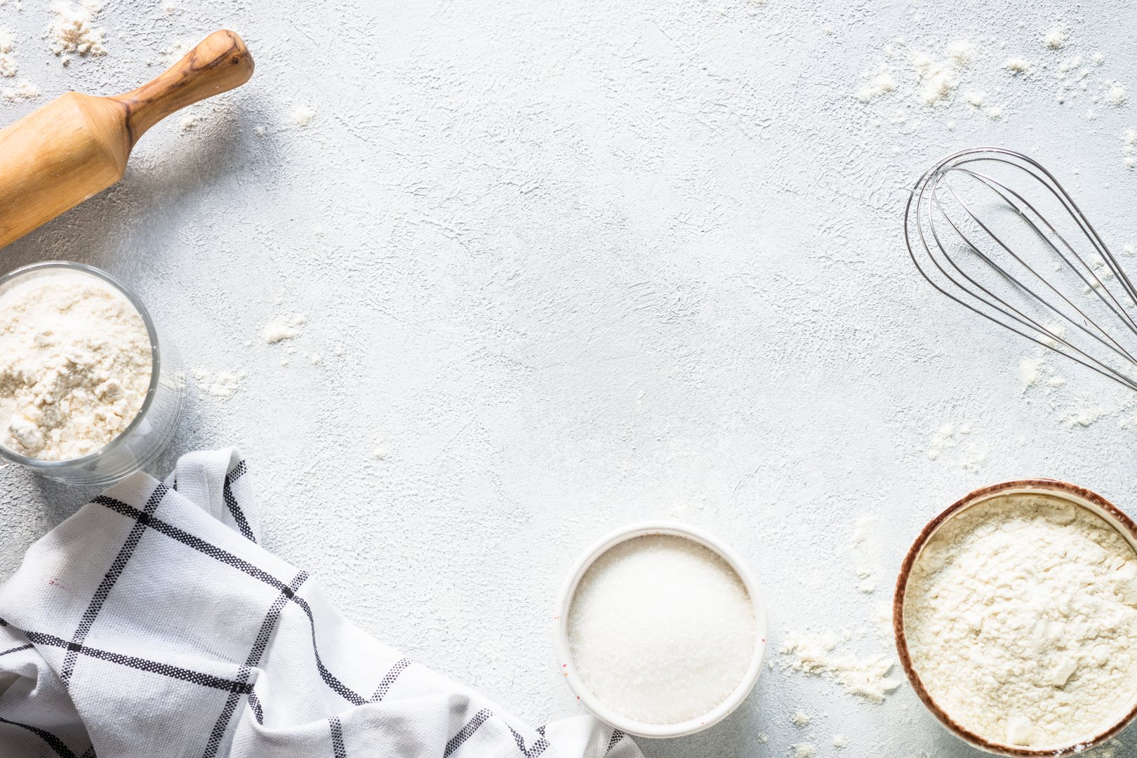 Baking background at light stone table. Flour, sugar, eggs and rolling pin. Top view with copy space.