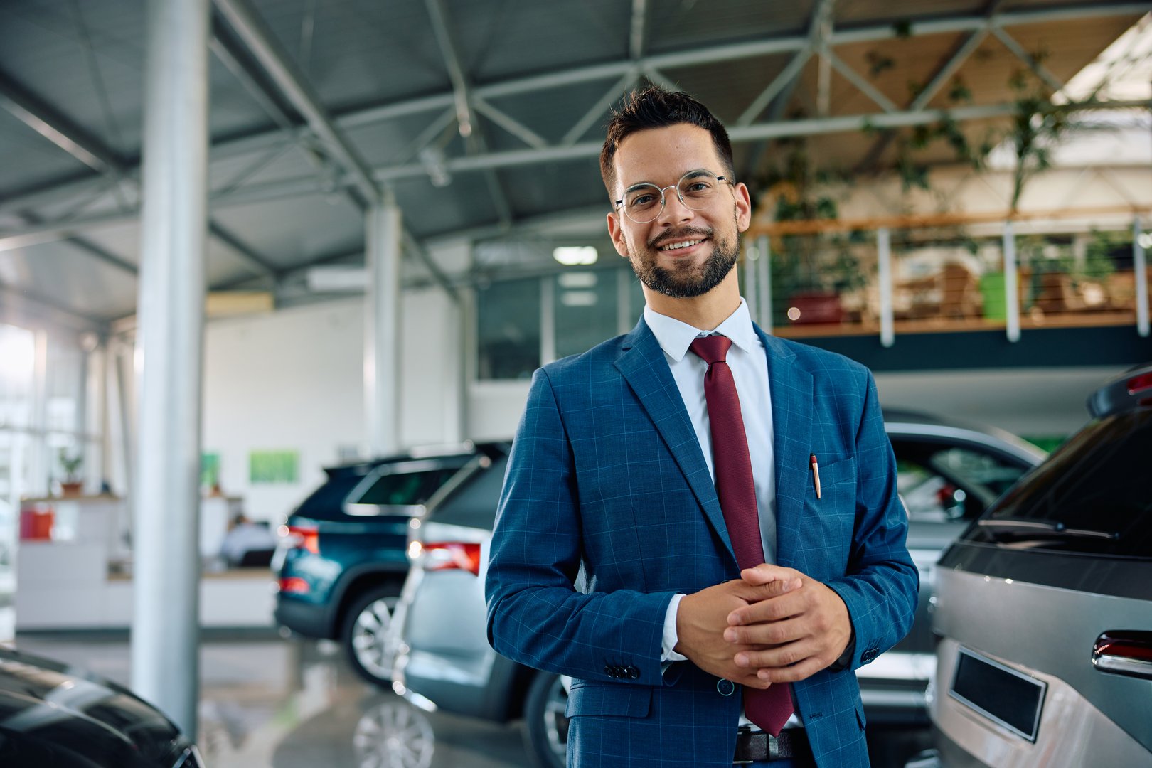 Happy car salesman in a showroom looking at camera. Copy space.