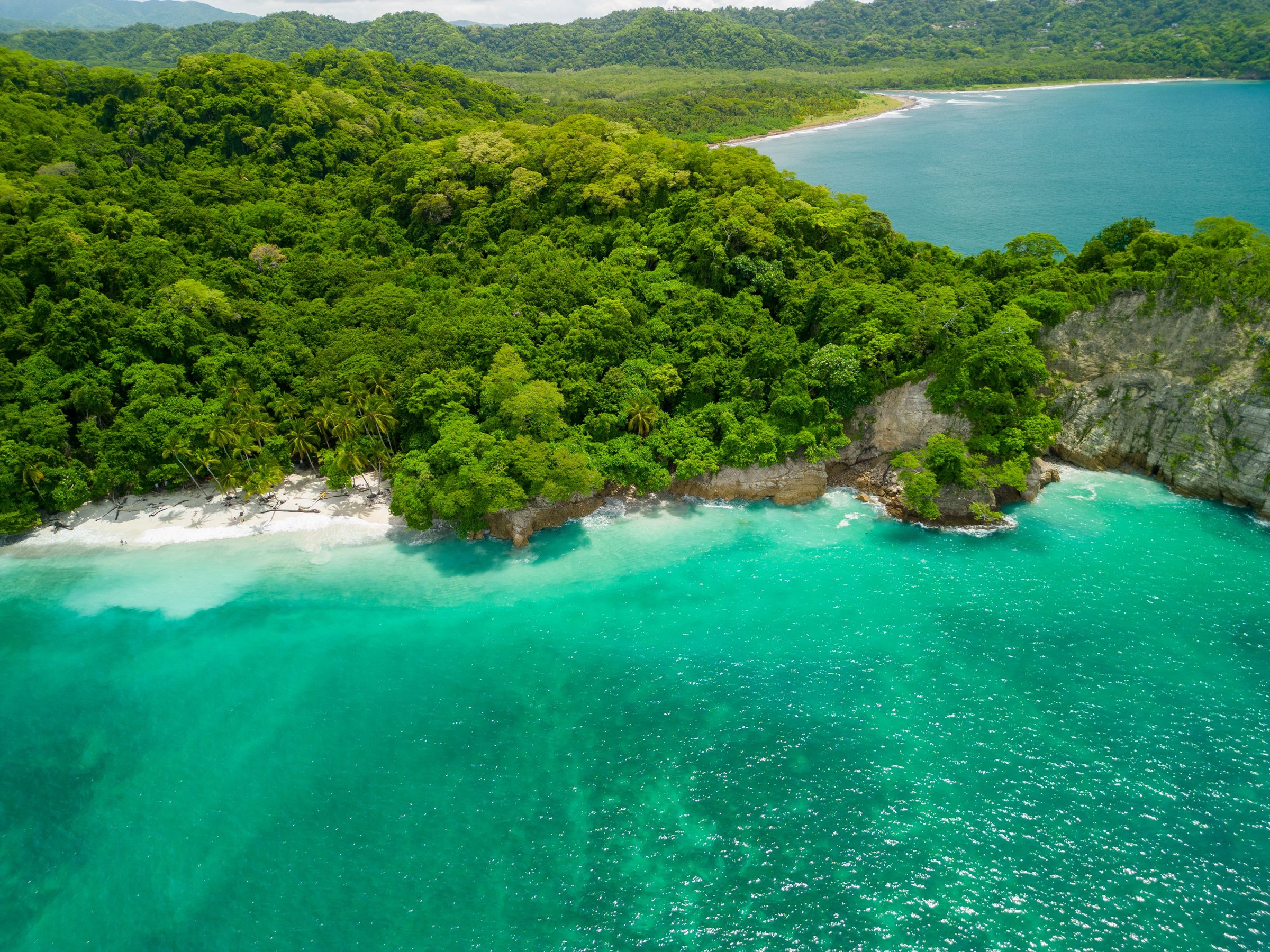Aerial view of a tropical beach with clear turquoise waters and lush greenery in Quesera beach, Pacific, Costa Rica