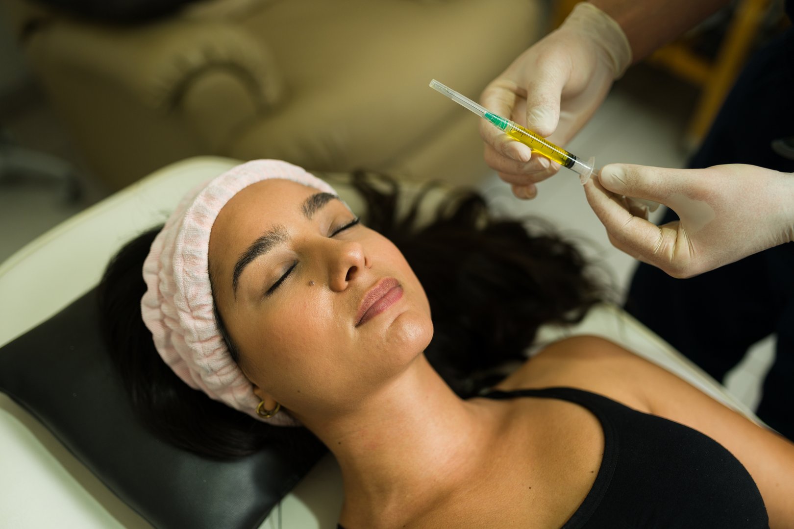 Beautiful latin woman getting platelet-rich plasma injections during a regenerative treatment at the alternative wellness clinic