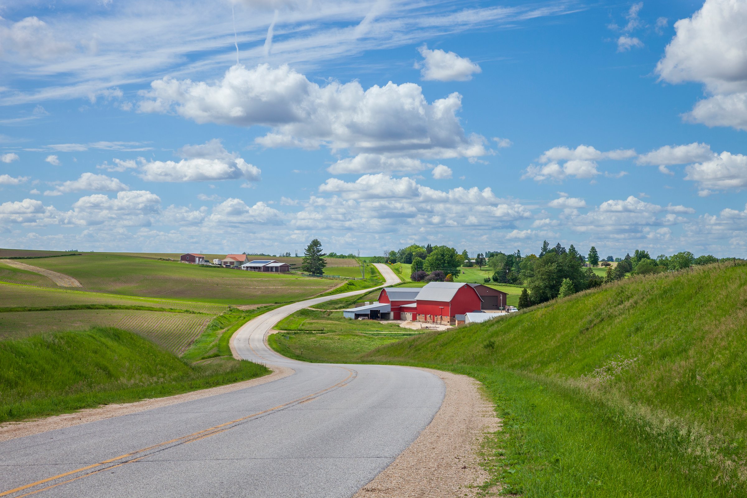 Farm with a red barn on a curving road in the Iowa countryside on a beautiful spring day