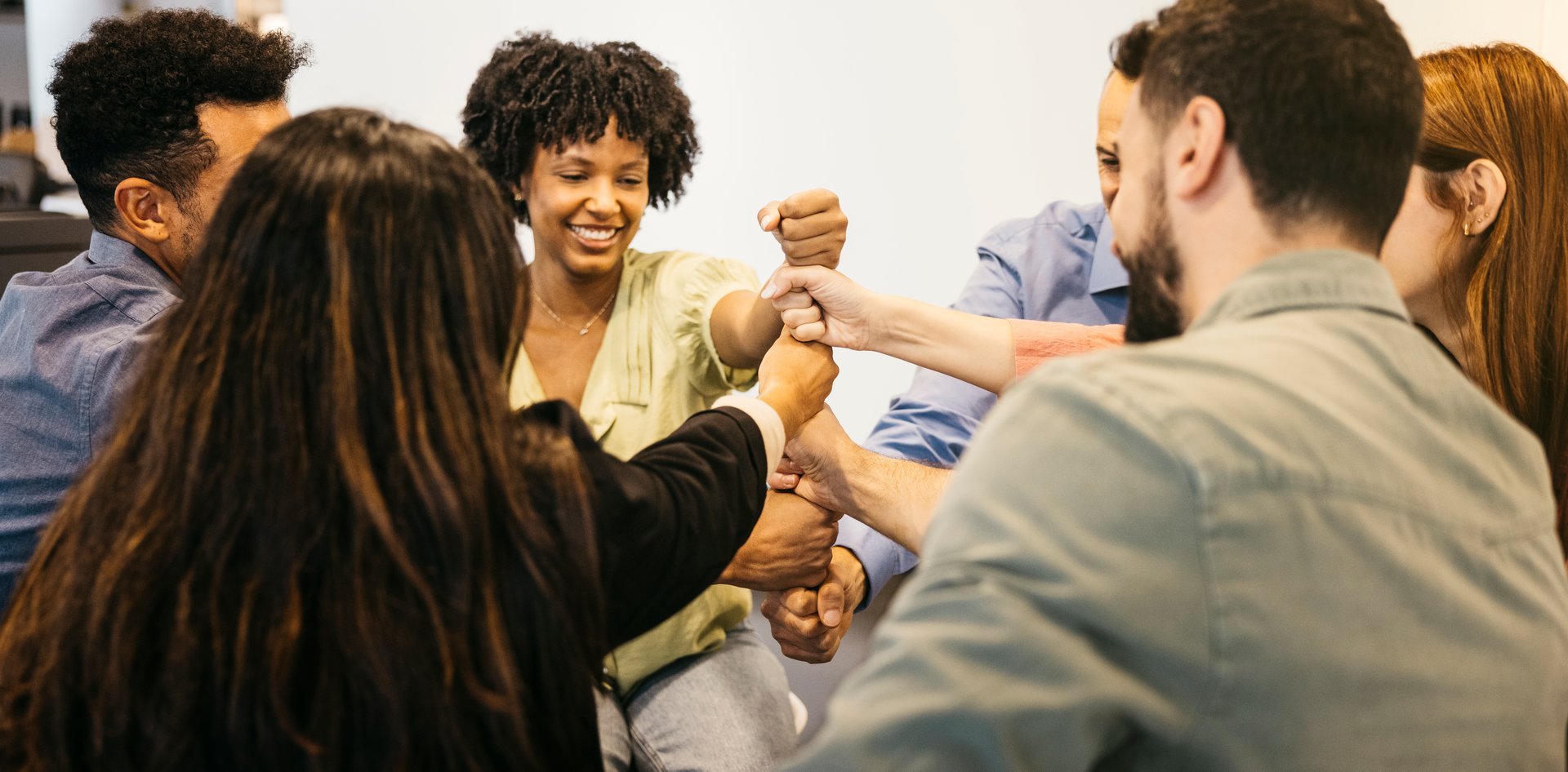 Diverse group of business people stacking hands, symbolizing teamwork and collaboration in the office