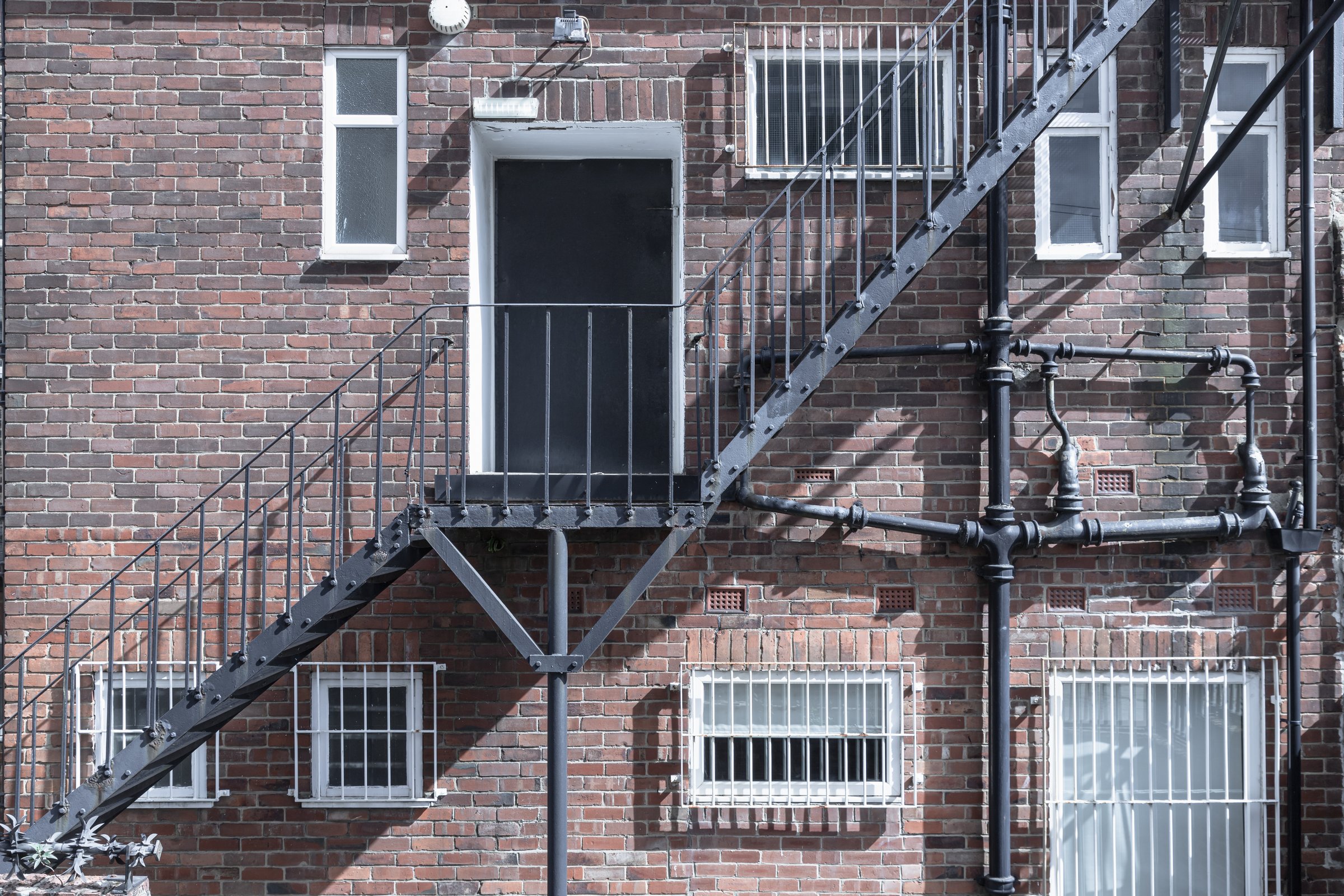 Newcastle, UK - Apr 13, 2025 - External Metal Staircase attached at the rear of old brick building in Newcastle. Urban architecture and emergency exit design, the metal rugged construction, perfectly integrated into the architectural of the building with a brick, use it as your Wallpaper, Poster and Space for text, Selective focus.