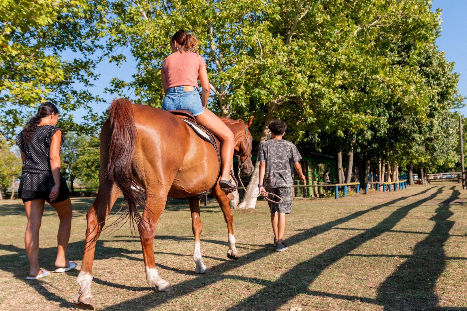 Instructor leading horse with woman rider at ranch