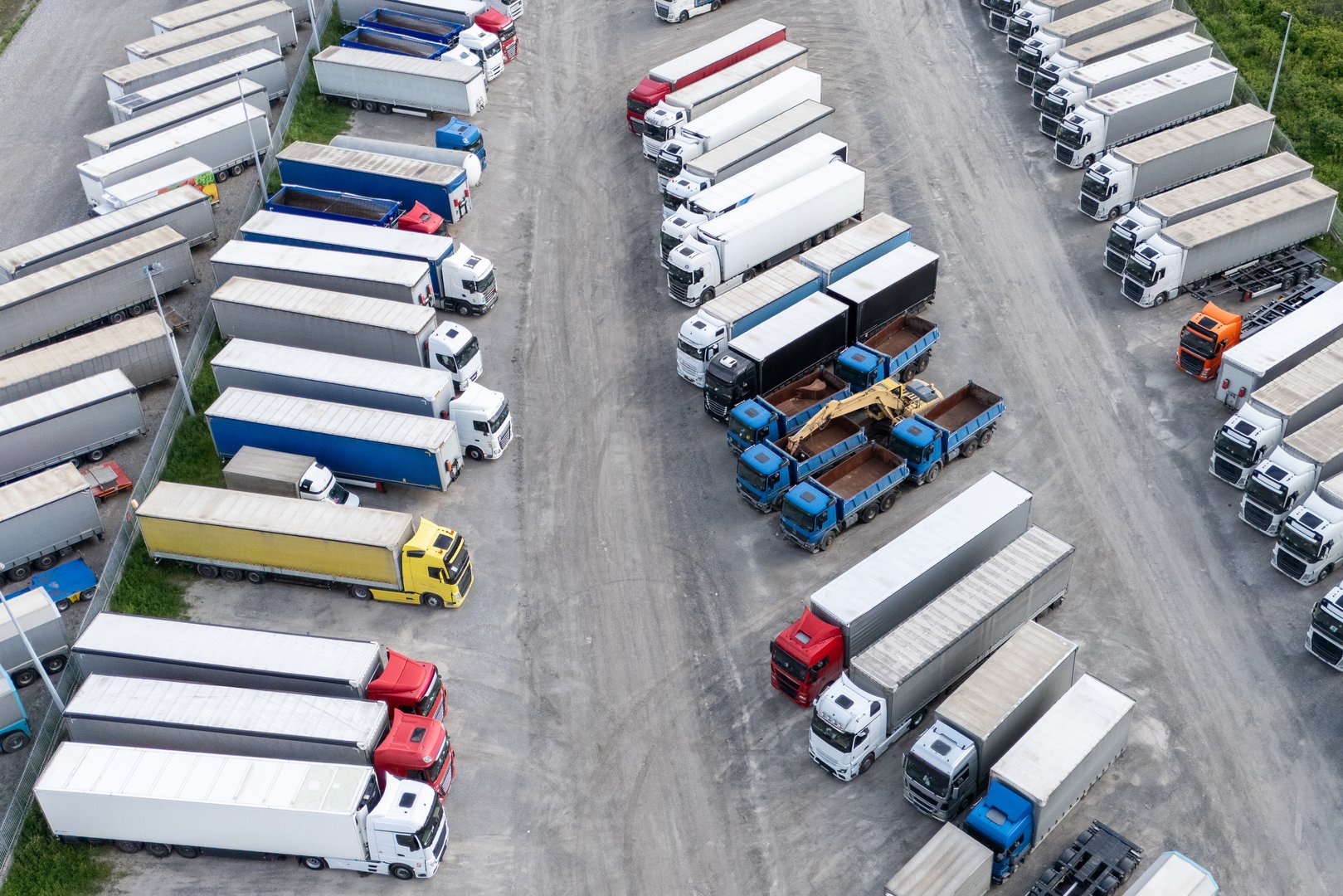 Aerial view of a large truck parking lot at a logistics hub, with multiple commercial semi trucks parked in organized rows