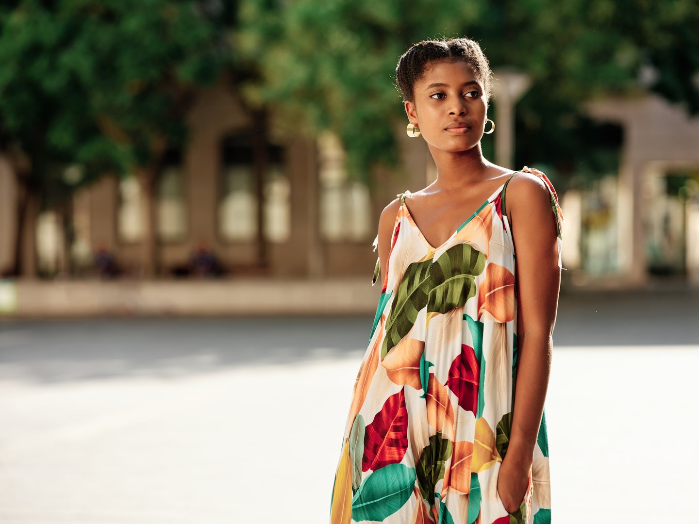 Young woman in dress looking away while walking outdoors.
