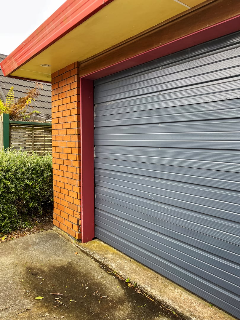 A modern garage exterior featuring a red brick wall with a broken corner