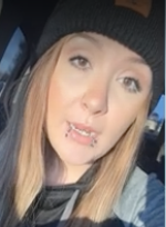 Person with long hair, beanie, and lip piercings, sitting in a car, likely taking a selfie.