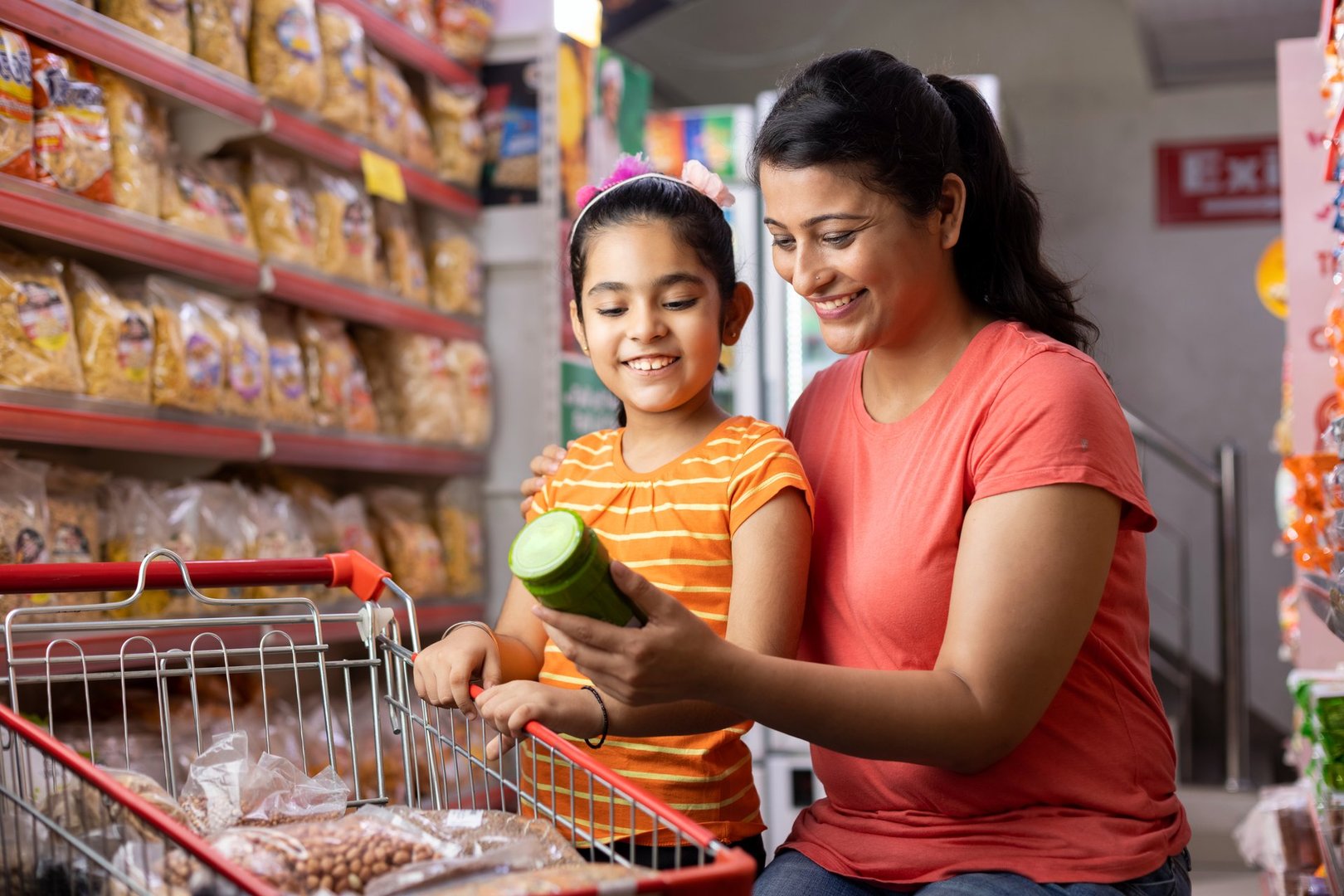 Mother and daughter reading product information while shopping at supermarket