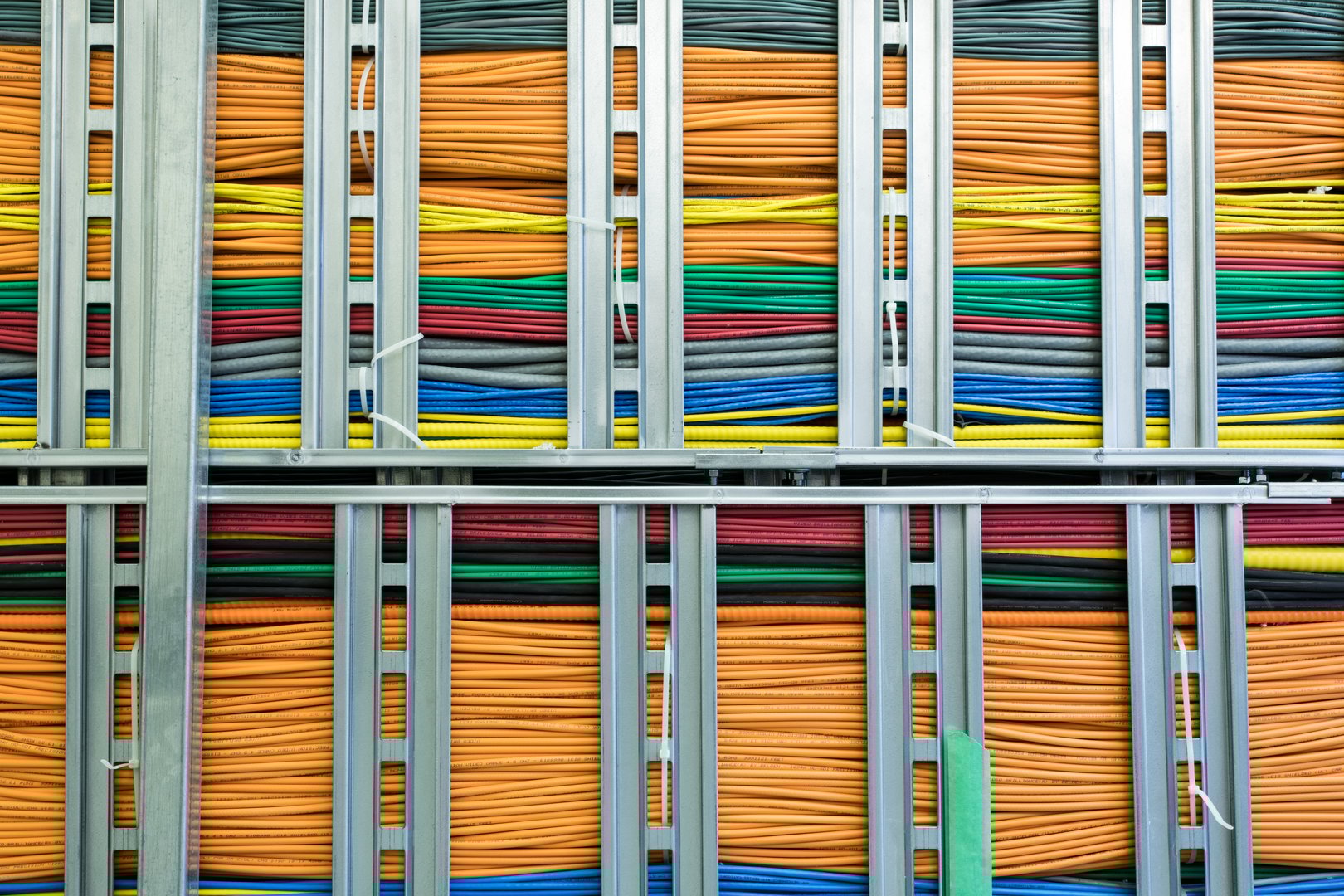 A large group of networking cables running through an office building.