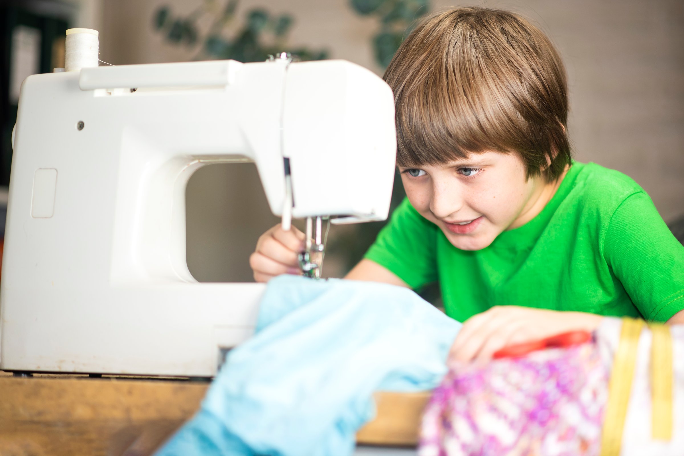handsome boy sewing clothes on a sewing machine at home